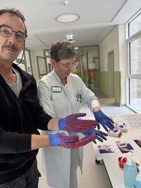 Zwei Personen, die Einmalhandschuhe mit Fingerfarbe anhaben