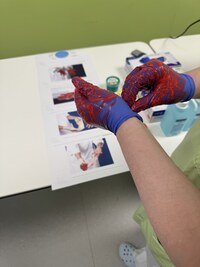 Hände mit Einmalhandschuhen mit Fingerfarbe